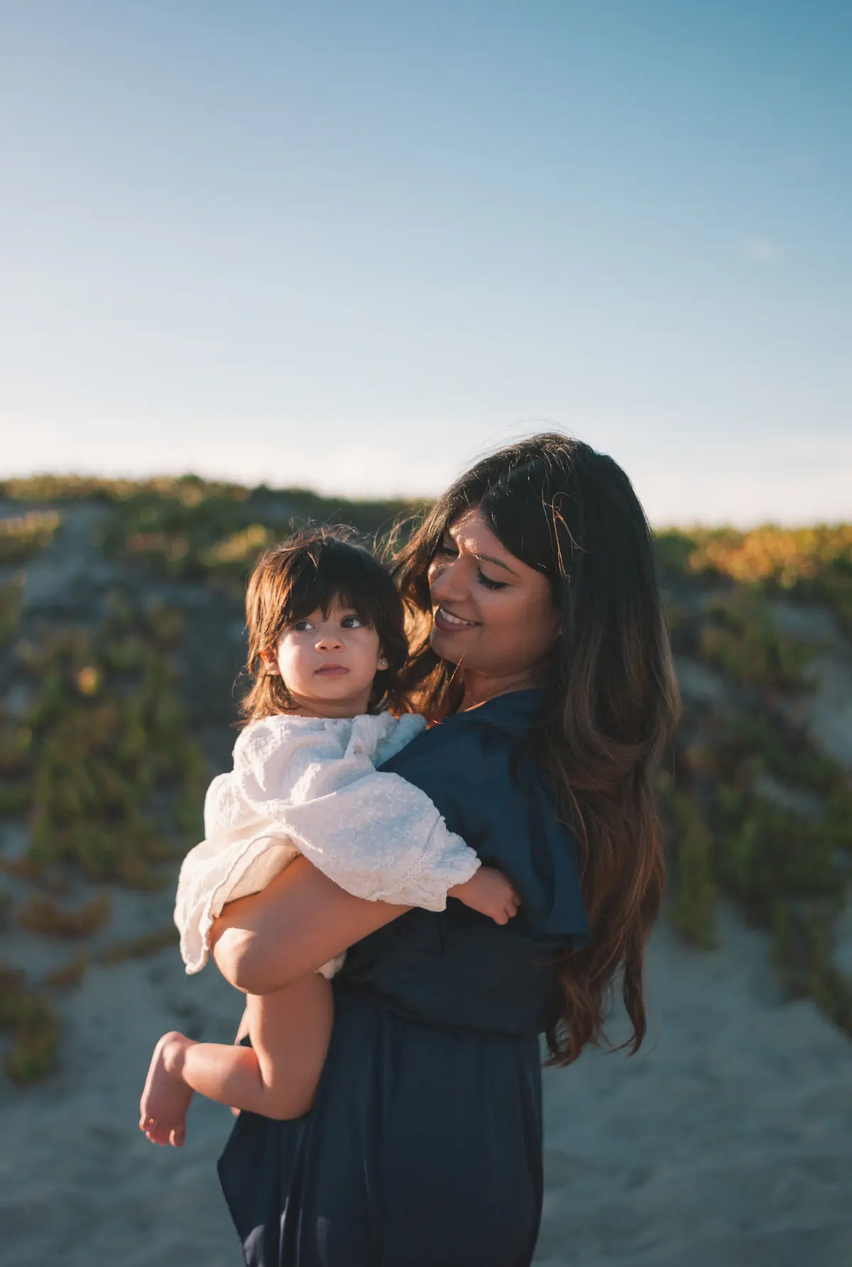 Mother holding her baby in golden-hour light on the Coronado dunes